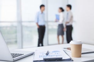 Close-up of office desk with business team behind